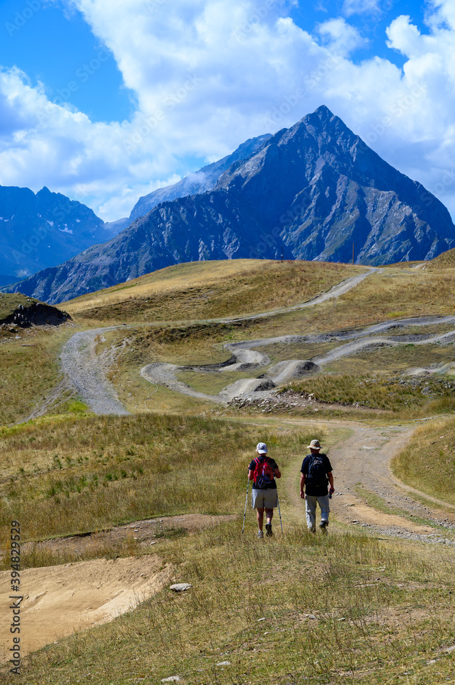 Old man and woman hiking in Ecrins alpine mountain range in summer, Les deux Alpes, France