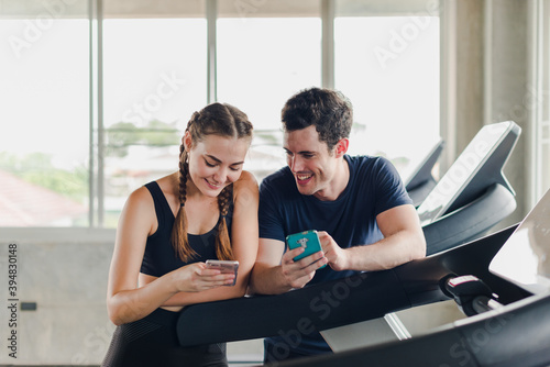 Couples exercise at the gym. Couple having fun playing with smartphones Near the exercise machine