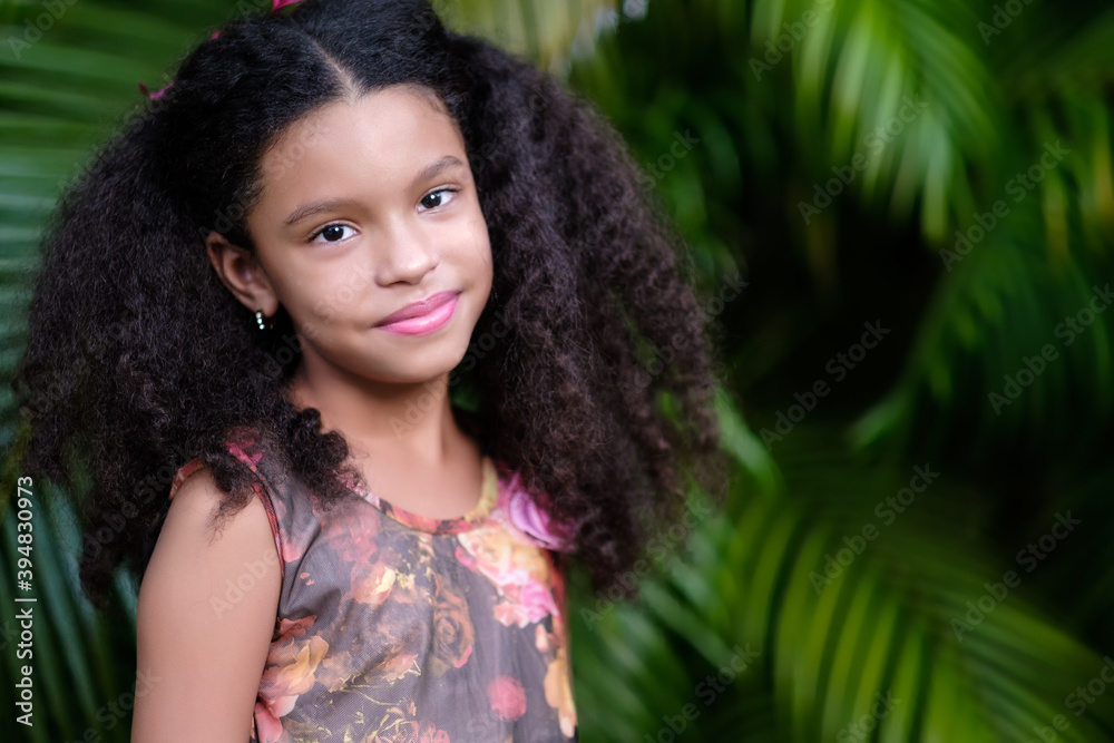 Portrait of a cute multiracial small girl with a green vegetation background Portrait of a cute multiracial small girl with a green vegetation background
