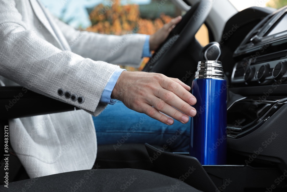 Man with thermos driving car, closeup view Man with thermos driving car, closeup view