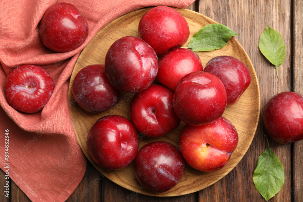 Delicious ripe plums on wooden table, flat lay Delicious ripe plums on wooden table, flat lay