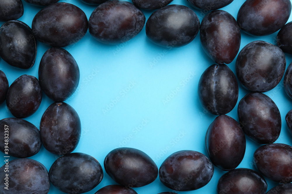 Frame made of delicious ripe plums on light blue background, flat lay. Space for text Frame made of delicious ripe plums on light blue background, flat lay. Space for text