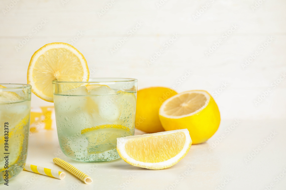 Soda water with lemon slices and ice cubes on white table. Space for text