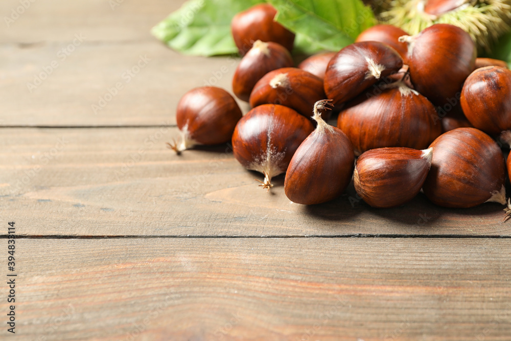 Fresh sweet edible chestnuts on wooden table, closeup. Space for text Fresh sweet edible chestnuts on wooden table, closeup. Space for text