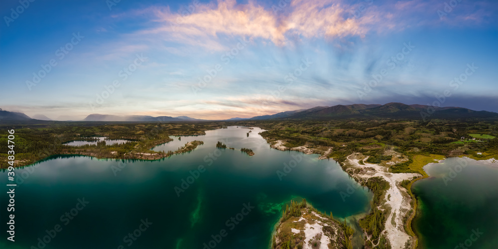 Beautiful Panoramic View of Scenic Lake, Islands and Forest in Canadian Nature. Colorful Sunset Sky. Aerial Done Shot taken near Klondike Highway. Lewes Lake, South of Whitehorse, Yukon, Canada.