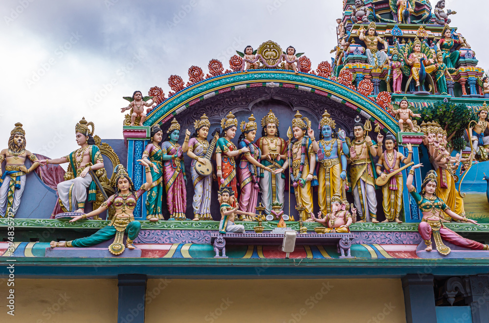 Kadirampura, Karnataka, India - November 4, 2013: Sri Murugan Temple. Closeup of colorful statues together representing wedding of Murugan set on top facade under blue cloudscape.