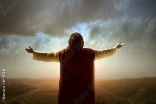 Fototapeta Rear view of Jesus Christ raised hands and praying to god