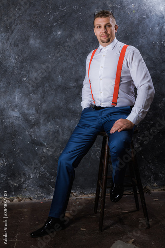 Mature businessman dressed in whire shirt with red suspenders studio portrait.