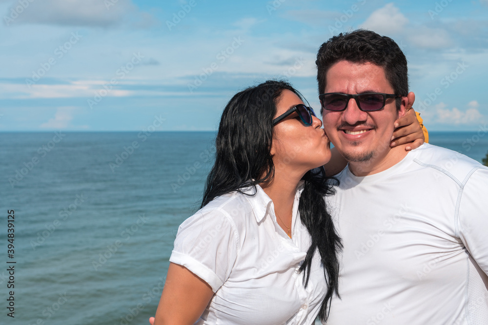 Woman kissing her boyfriend on the cheek at the beach Woman kissing her boyfriend on the cheek at the beach