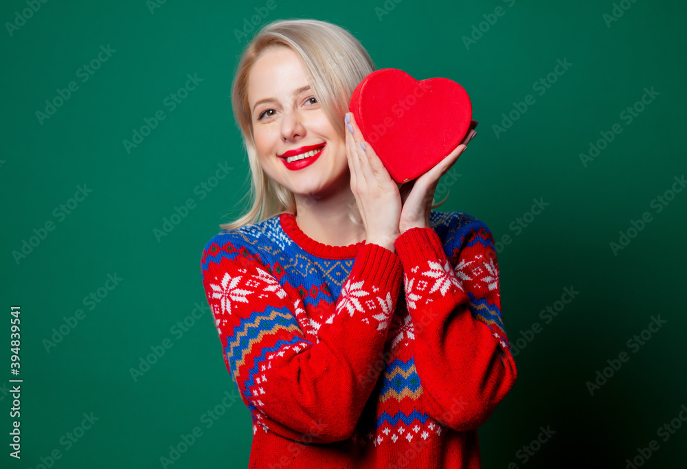 Beautiful woman in Christmas sweater with heart shape gift box Beautiful woman in Christmas sweater with heart shape gift box