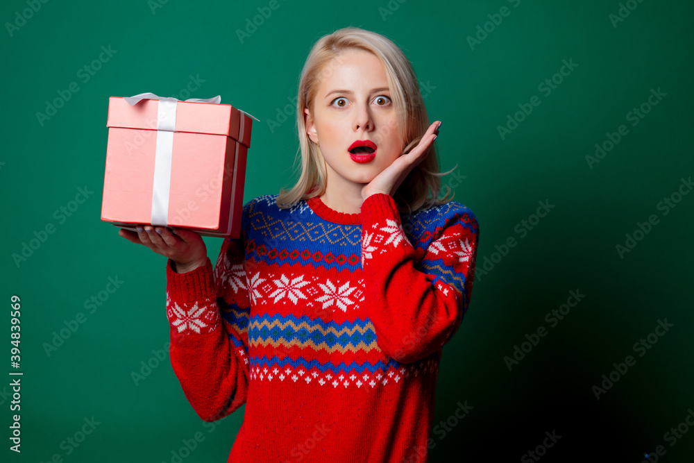 Beautiful woman in Christmas sweater with gift box on green background Beautiful woman in Christmas sweater with gift box on green background