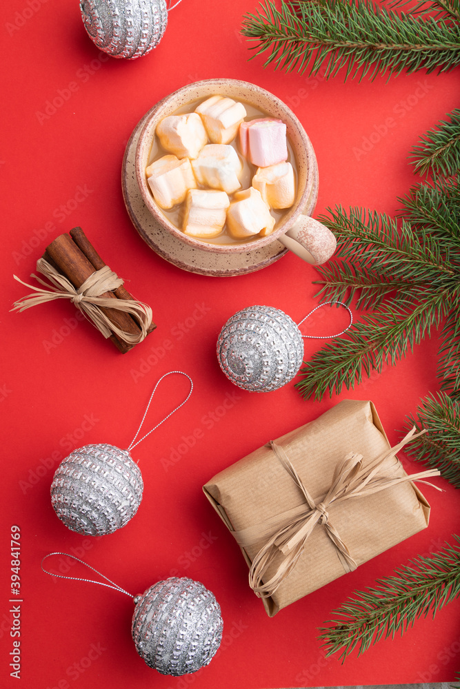 Fototapeta premium Christmas or New Year composition. Decorations, silver balls, fir and spruce branches, cup of coffee, on a red background. Top view.