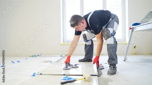 industrial tiler Professional builder worker installing floor a large ceramic tile at repair renovation work. Man experienced repairman laying placing tile indoors house or apartment. Finishing works