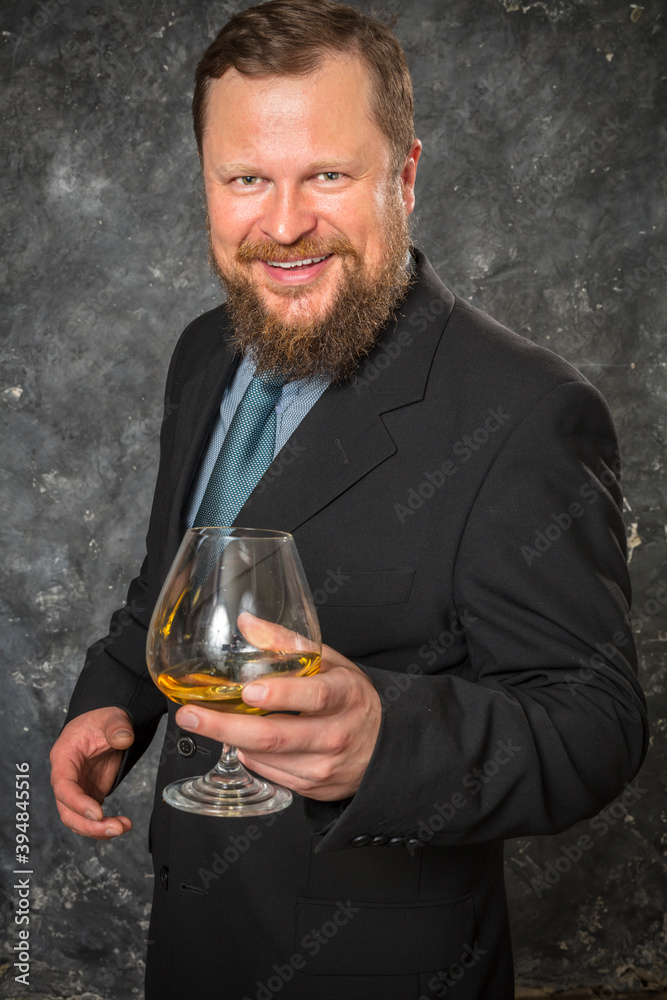Solid smiling bearded man in suit with glass of whisky Solid smiling bearded man in suit with glass of whisky