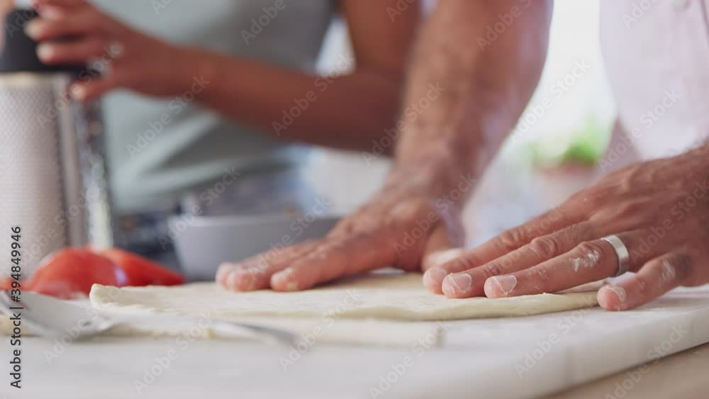Close up of couple at home in kitchen preparing base and grating cheese for topping on homemade pizza - shot in slow motion Close up of couple at home in kitchen preparing base and grating cheese for topping on homemade pizza - shot in slow motion