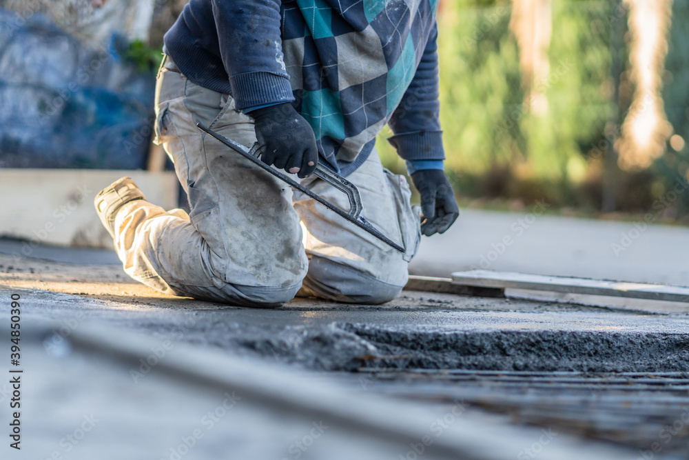 Close up on midsection of unknown worker spreading concrete cement mortar on the ground in day at construction site Close up on midsection of unknown worker spreading concrete cement mortar on the ground in day at construction site