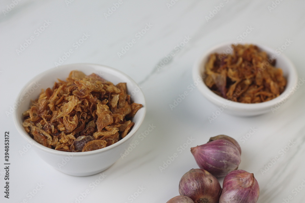 Bawang Merah Goreng or fried shallots, popular Indonesian food topping. Served on white ceramic bowl. Isolated background, copy space. Bawang Merah Goreng or fried shallots, popular Indonesian food topping. Served on white ceramic bowl. Isolated background, copy space.