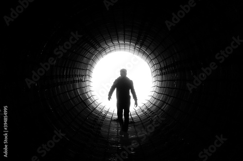 Silhouette of a man walking to the light at the end of a big tunnel. Concept of escape, exit, freedom, clinical death