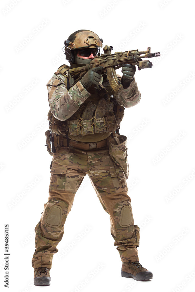 Full length portrait of soldier in combat ammunition in hard hat and glasses with a weapon equipped with collimator sight is aiming at the enemy ready to shoot to kill isolated on white background Full length portrait of soldier in combat ammunition in hard hat and glasses with a weapon equipped with collimator sight is aiming at the enemy ready to shoot to kill isolated on white background