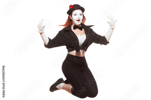 Portrait of female mime artist performing, isolated on white background. Woman jumps very high smiling
