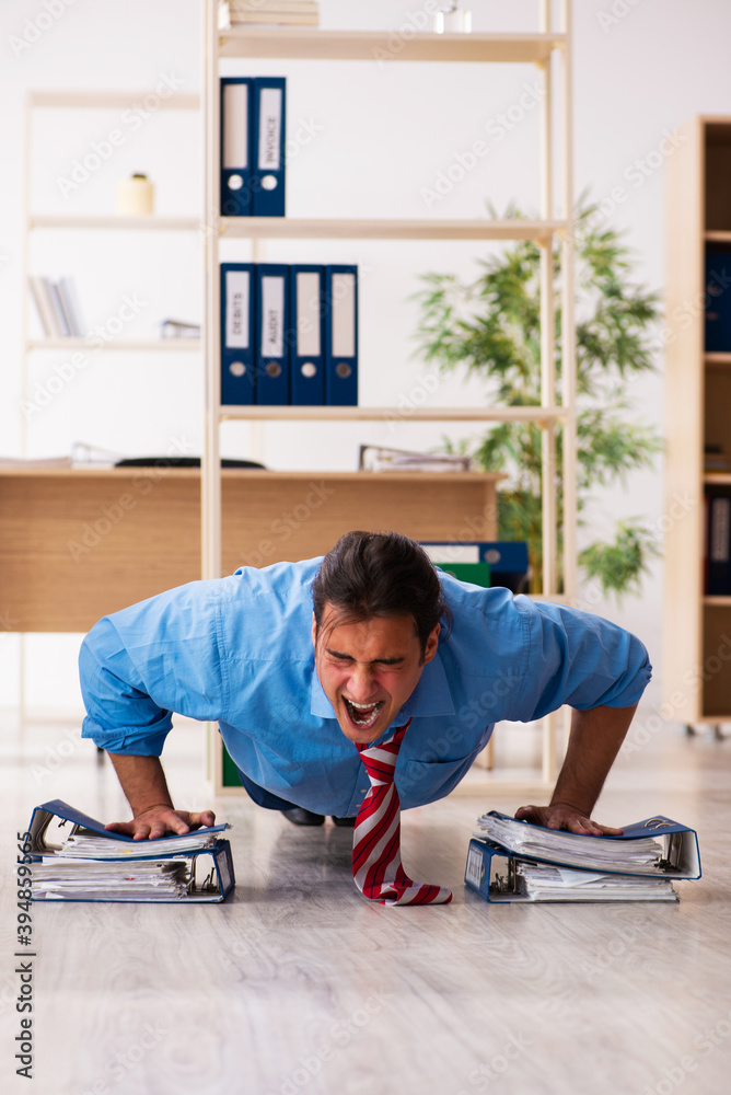 Young male employee doing sport exercises at workplace Young male employee doing sport exercises at workplace