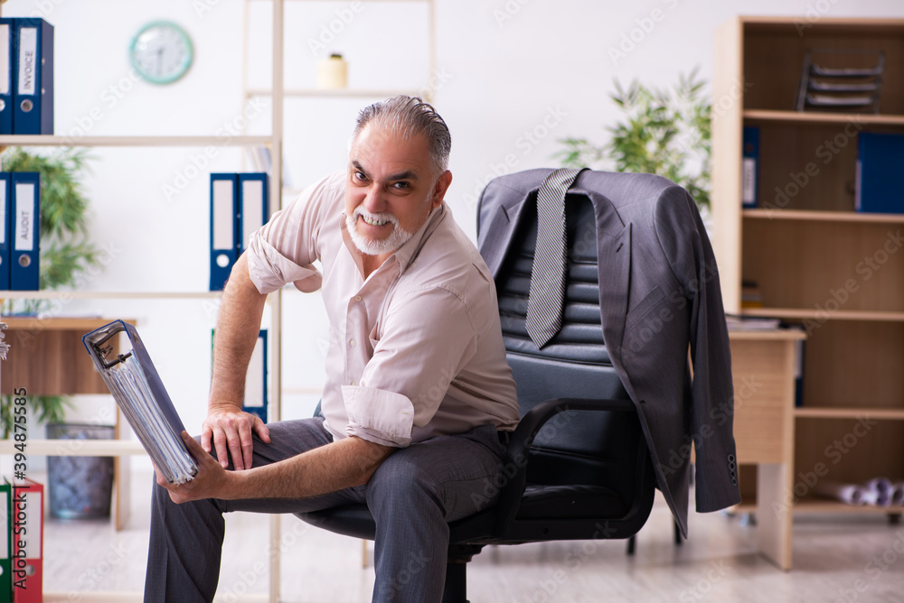 Old male employee doing physical exercises at workplace Old male employee doing physical exercises at workplace