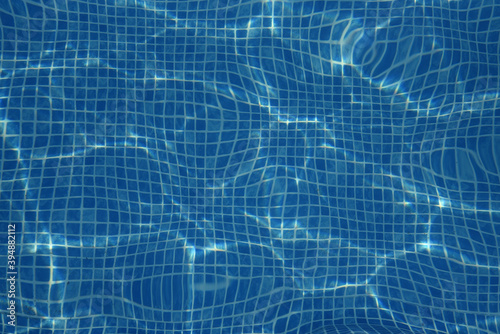 Small blue tiles in the pool. The bottom of the pool is visible through the clear water. Background  texture
