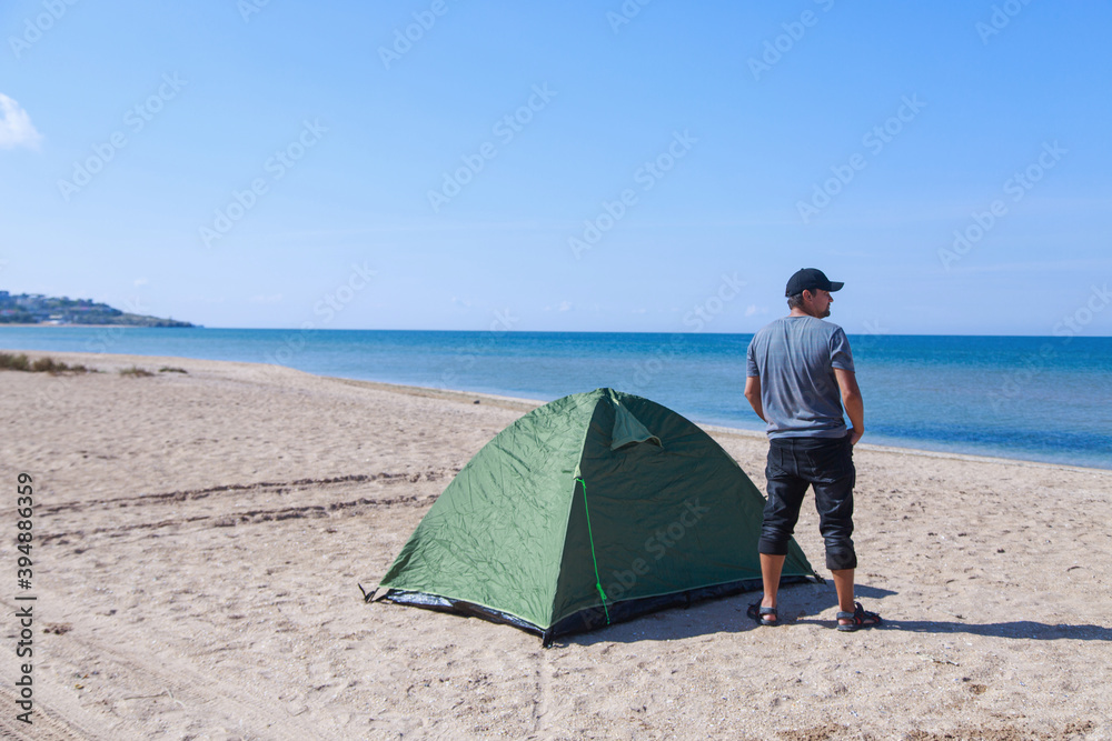journey to the sea. camping on the beach. Vacation by the water. Man and tent on the sand