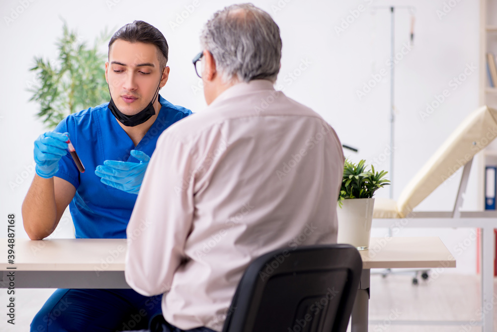 Fototapeta premium Old patient visiting young male doctor in blood sampling concept