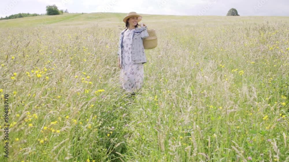 Young woman standing in meadow with woven basket full of flowers slow motion. Flora, nature, environment footage concept. Young woman standing in meadow with woven basket full of flowers slow motion. Flora, nature, environment footage concept.