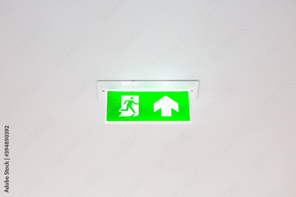 Emergency exit signboard on white ceiling background and copy space Emergency exit signboard on white ceiling background and copy space