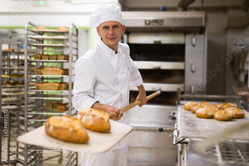 Fotografie, Obraz male baker with bread on baking shovel in kitchen