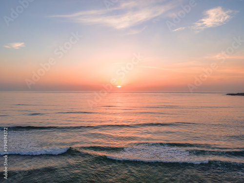 Soft haze and pastel coloured sunrise seascape © Merrillie