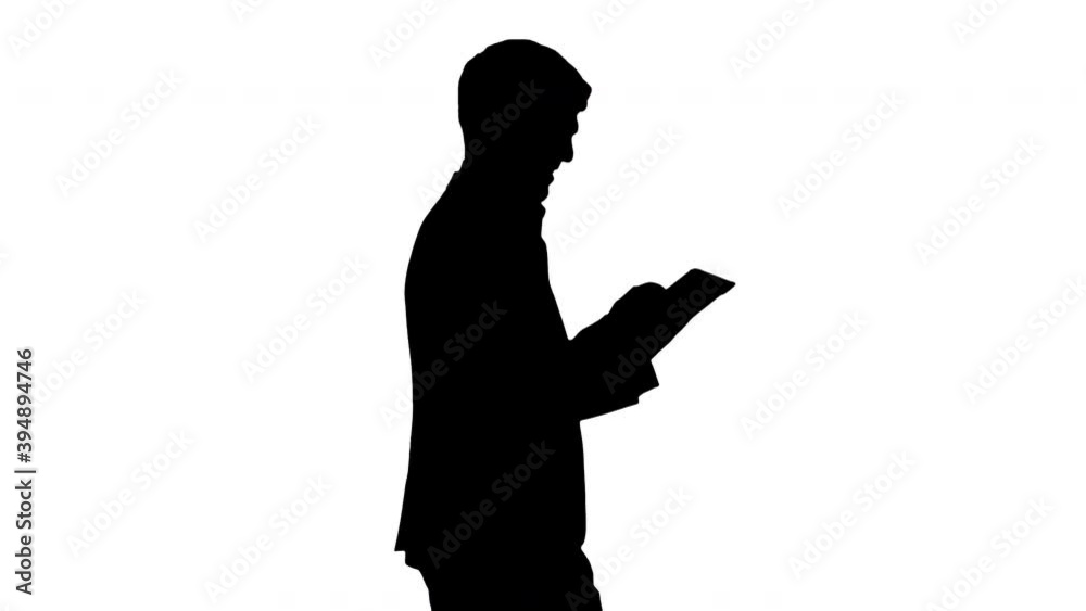 Silhouette Smiling businessman using digital tablet while walking. Silhouette Smiling businessman using digital tablet while walking.