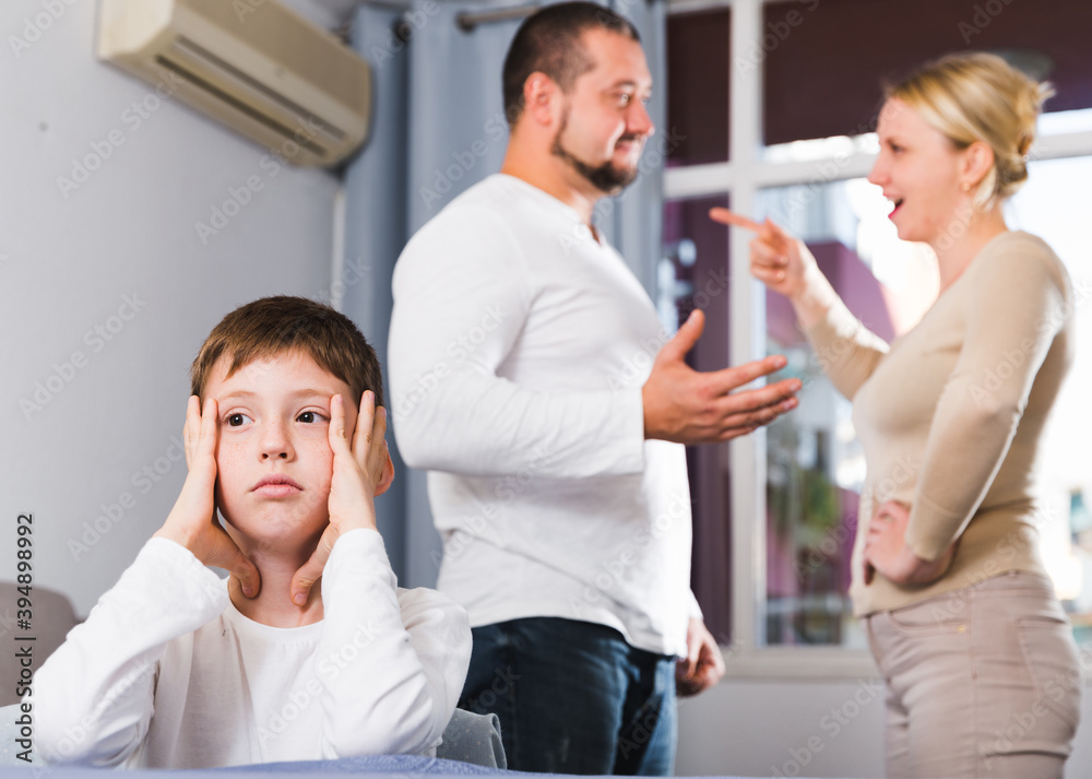Obraz premium Portrait of unhappy boy sitting at home while parents quarreling