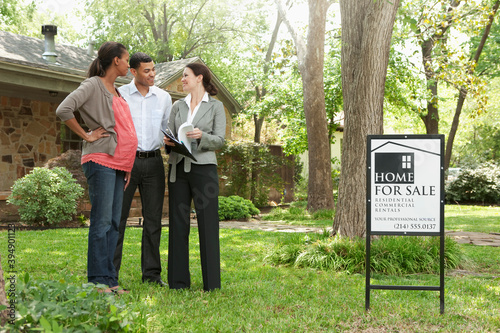 Couple and realtor looking at home for sale photo