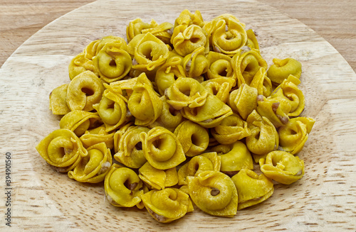 Raw Tortellini in a wooden bowl on wooden table. Traditional italian pasta. 