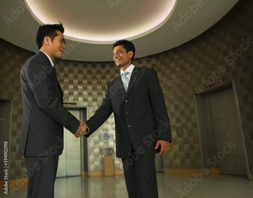 Businessmen shaking hands in office lobby