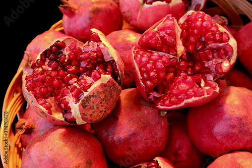 Closeup Vibrant Red Opened Fresh Pomegranate Fruits on the Whole Fruit Pile photo