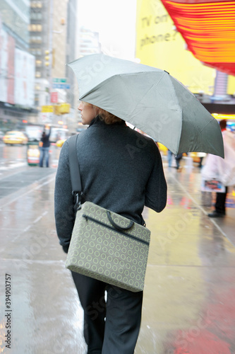 Caucasian businessman walking in rain with umbrella