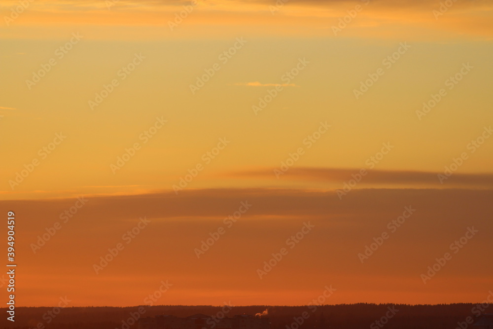 Sun below the horizon and clouds in the fiery dramatic orange sky at sunset or dawn backlit by the sun. Place for text and design