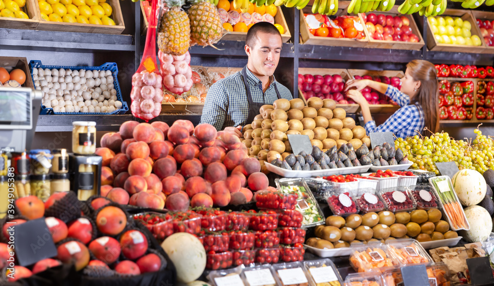 Obraz premium Portrait of male and female young shop assistants working responsibly in a fruit and vegetable shop