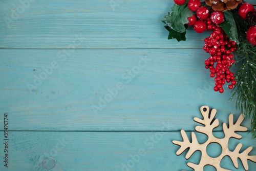On a turquoise wood background  a decoration of a fir branch  cones and wood snowflakes. Christmas background.