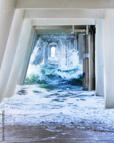 Waves rushing to shore under steel pier