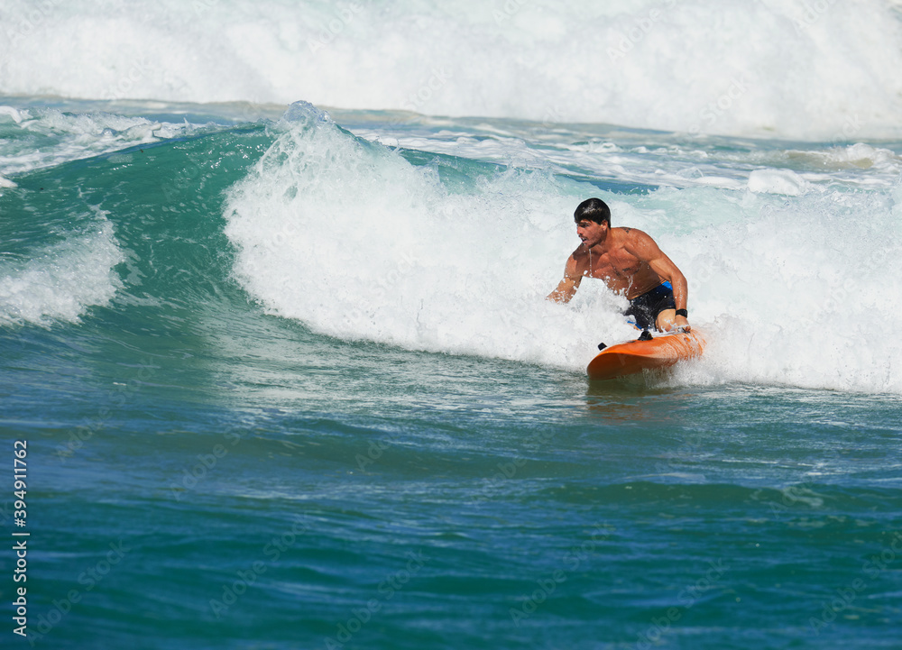 Male Surf Lifesaver riding a wave on ocean surf ski Male Surf Lifesaver riding a wave on ocean surf ski