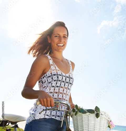 Young woman standing and holding bicycle and smiling photo