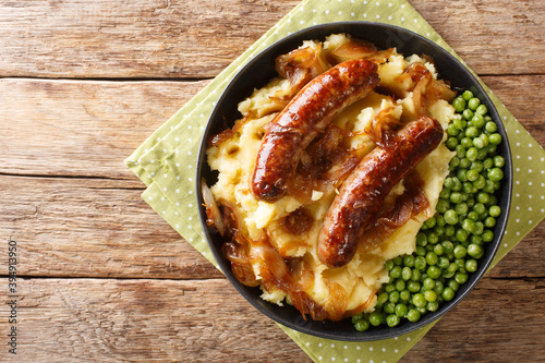 Schilderij op canvas Fried sausages with mashed potatoes, onion gravy and green peas close-up in a plate on the table