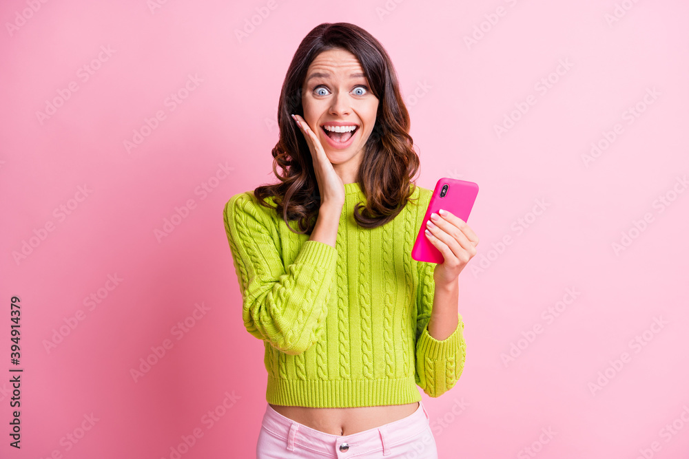 Photo of impressed wavy lady wear green sweater holding modern device arm cheek isolated pink color background Photo of impressed wavy lady wear green sweater holding modern device arm cheek isolated pink color background