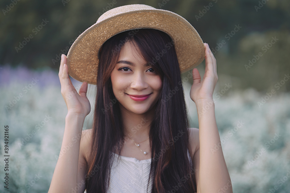 Happy Asian woman wear white dress and straw hat walking in white cutter flowers garden