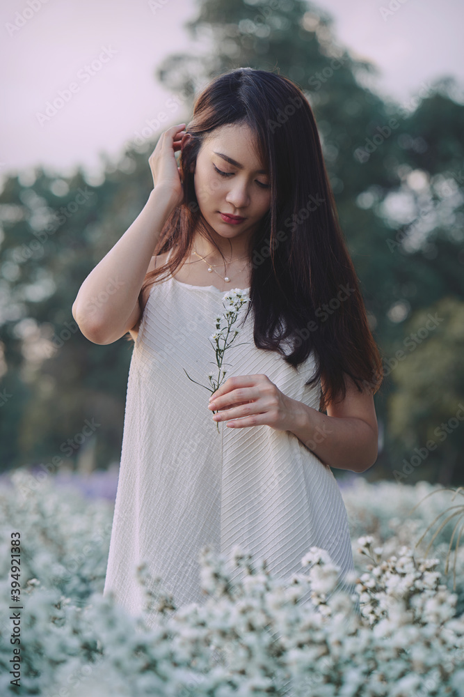 Happy Asian woman wear white dress walking in white cutter flowers garden